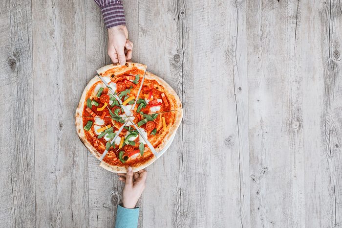 hands grabbing slices of pizza