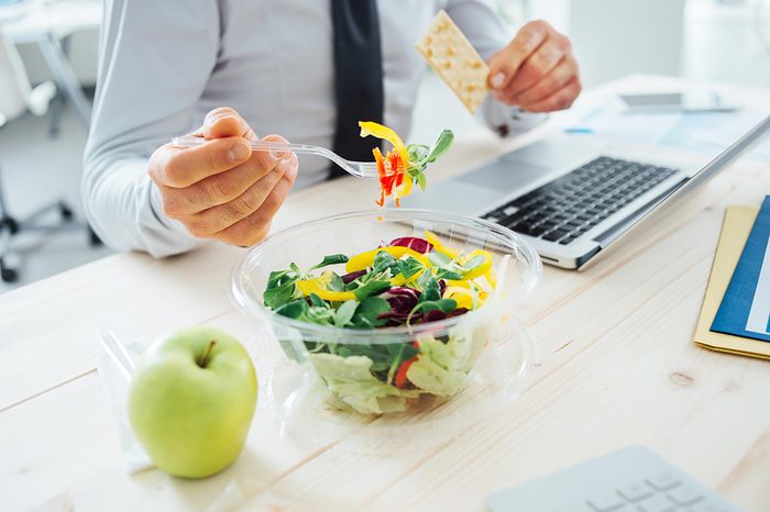 business man eating a salad at his desk