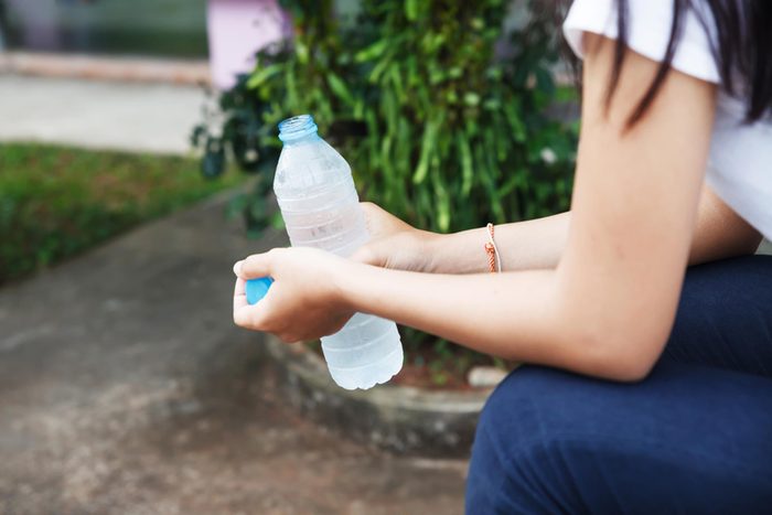 woman sitting outside holding an open plastic water bottle