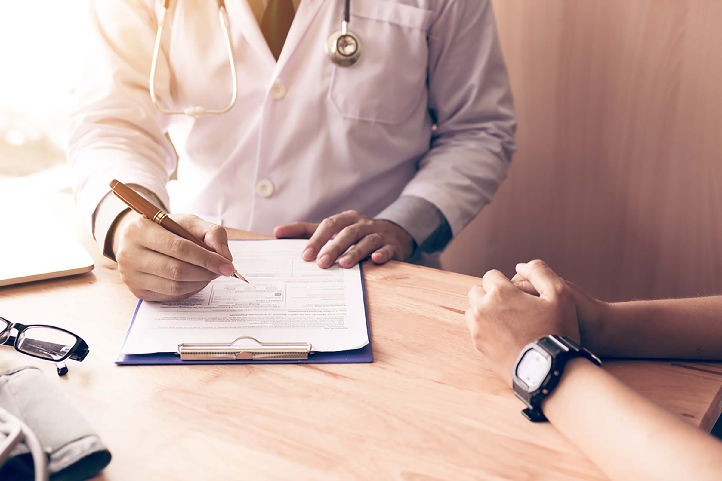 doctor with patient, writing on a clipboard