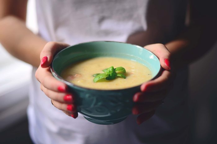 Woman carrying a bowl of soup.