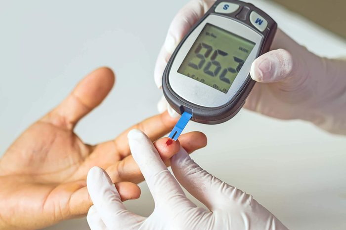 Blood pressure monitor pricking finger and showing blood glucose levels