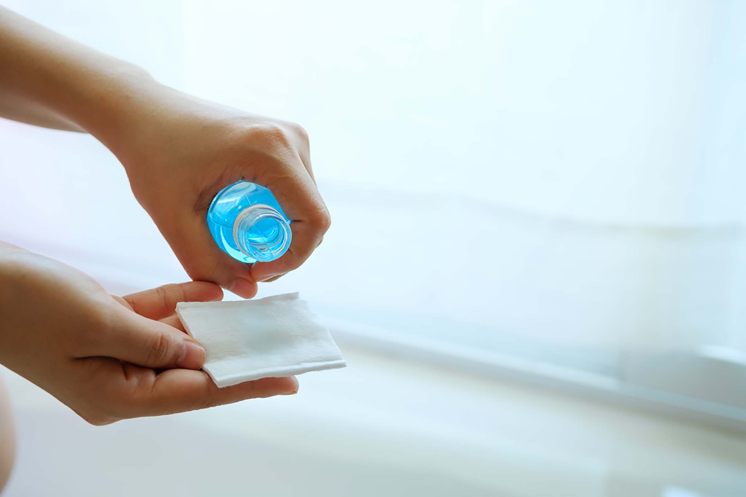 woman pouring rubbing Alcohol on a pad