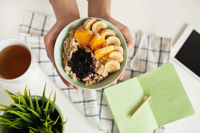 Person holding a bowl of oatmeal with fruit.