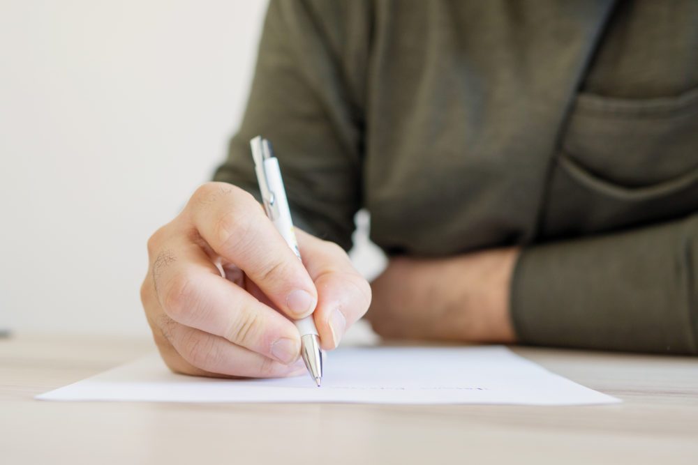 close up of man writing on paper