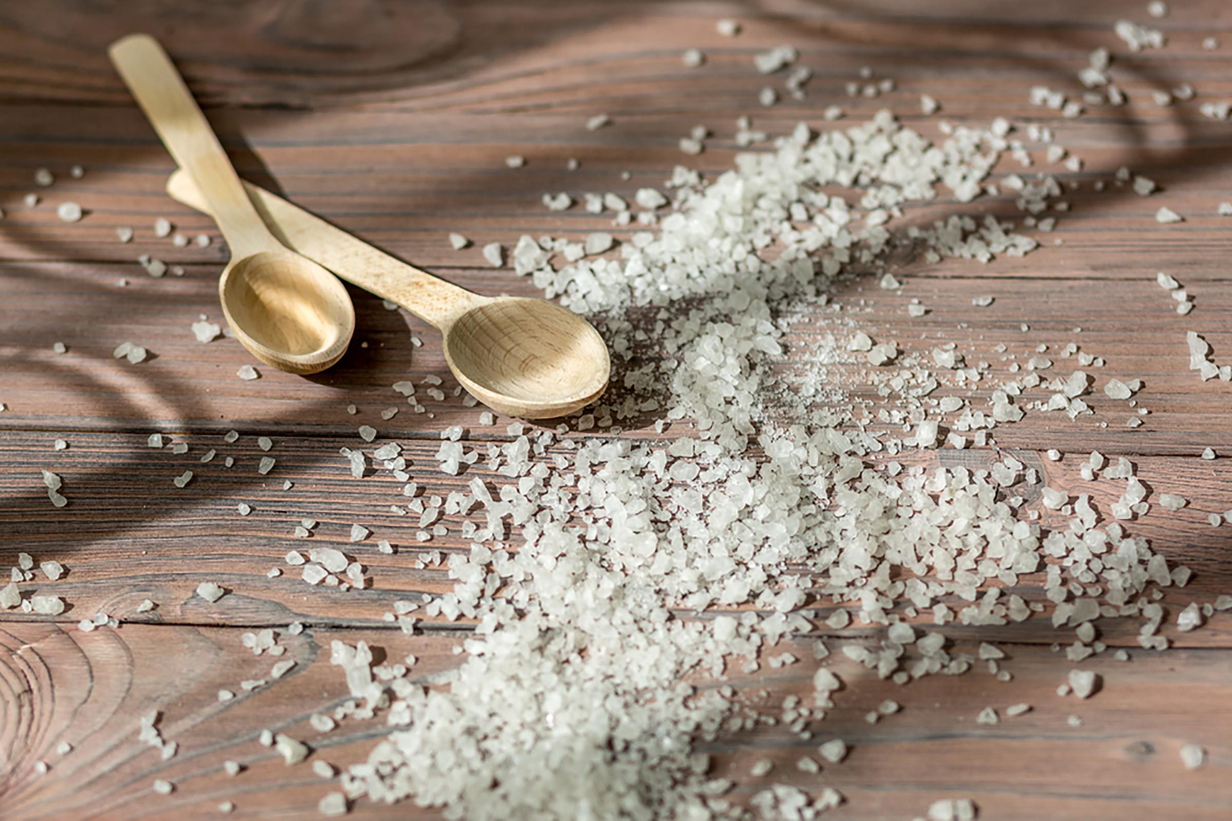 Epsom salt scattered on a wooden table; wooden spoons