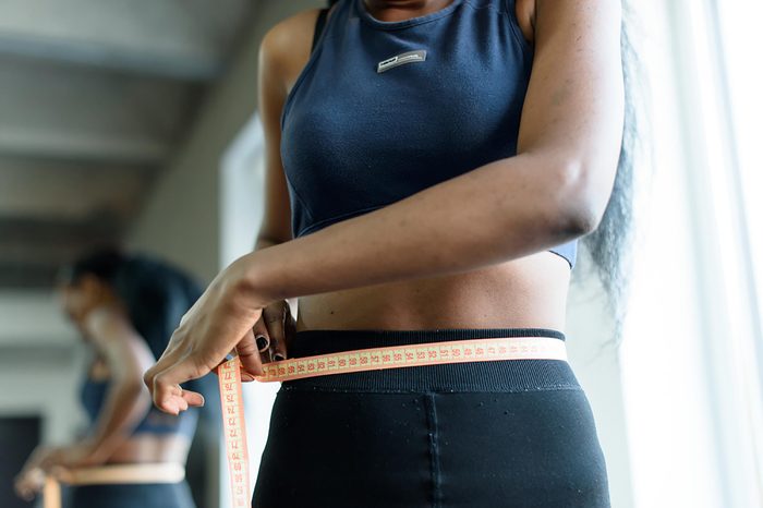 Slim woman measuring her waist with a tape measure