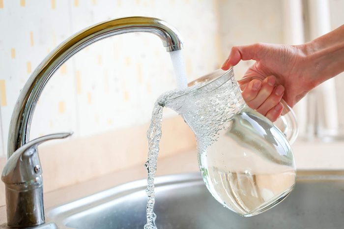 faucet filling glass pitcher full of water