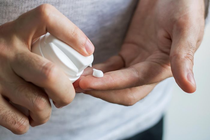 Man squeezing a dab of cream onto his finger.