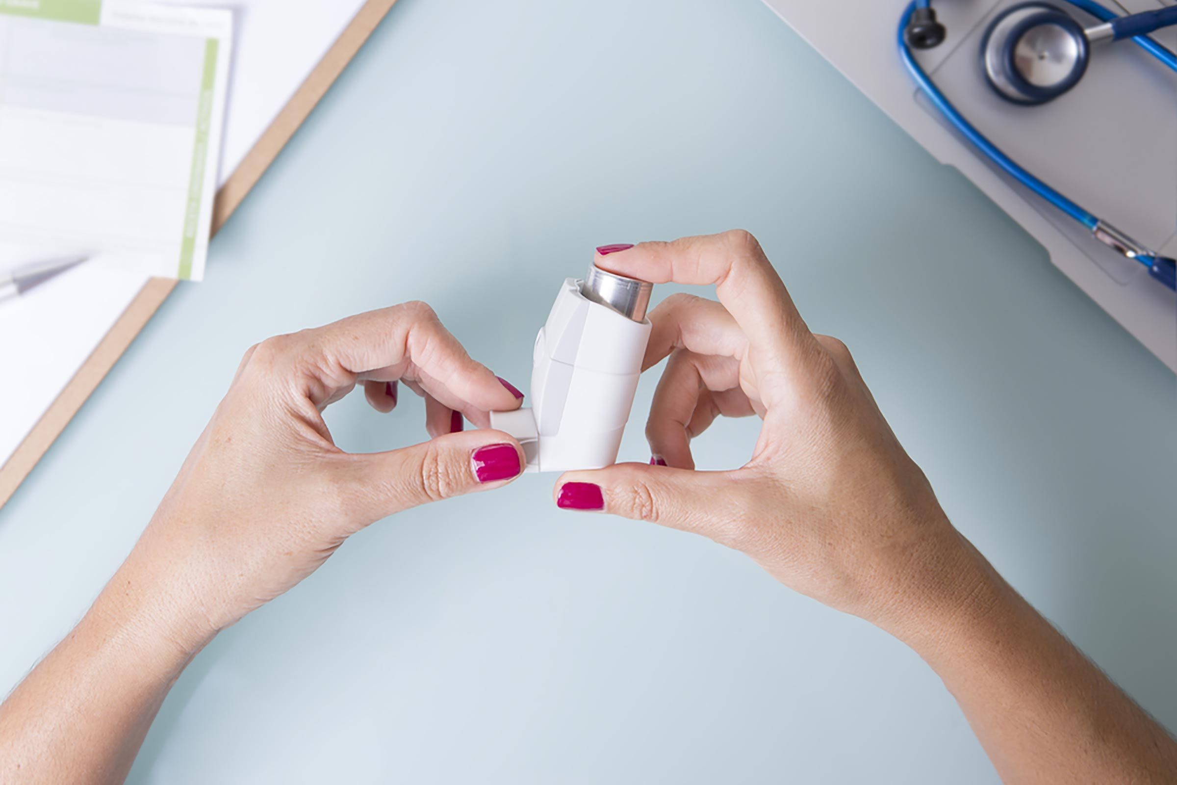 woman holding an asthma inhaler