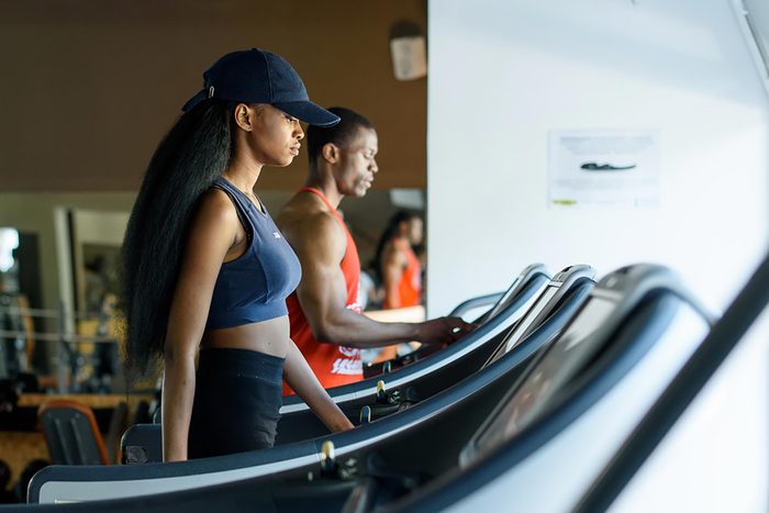 Woman in a baseball cap walking on a treadmill at the gym.