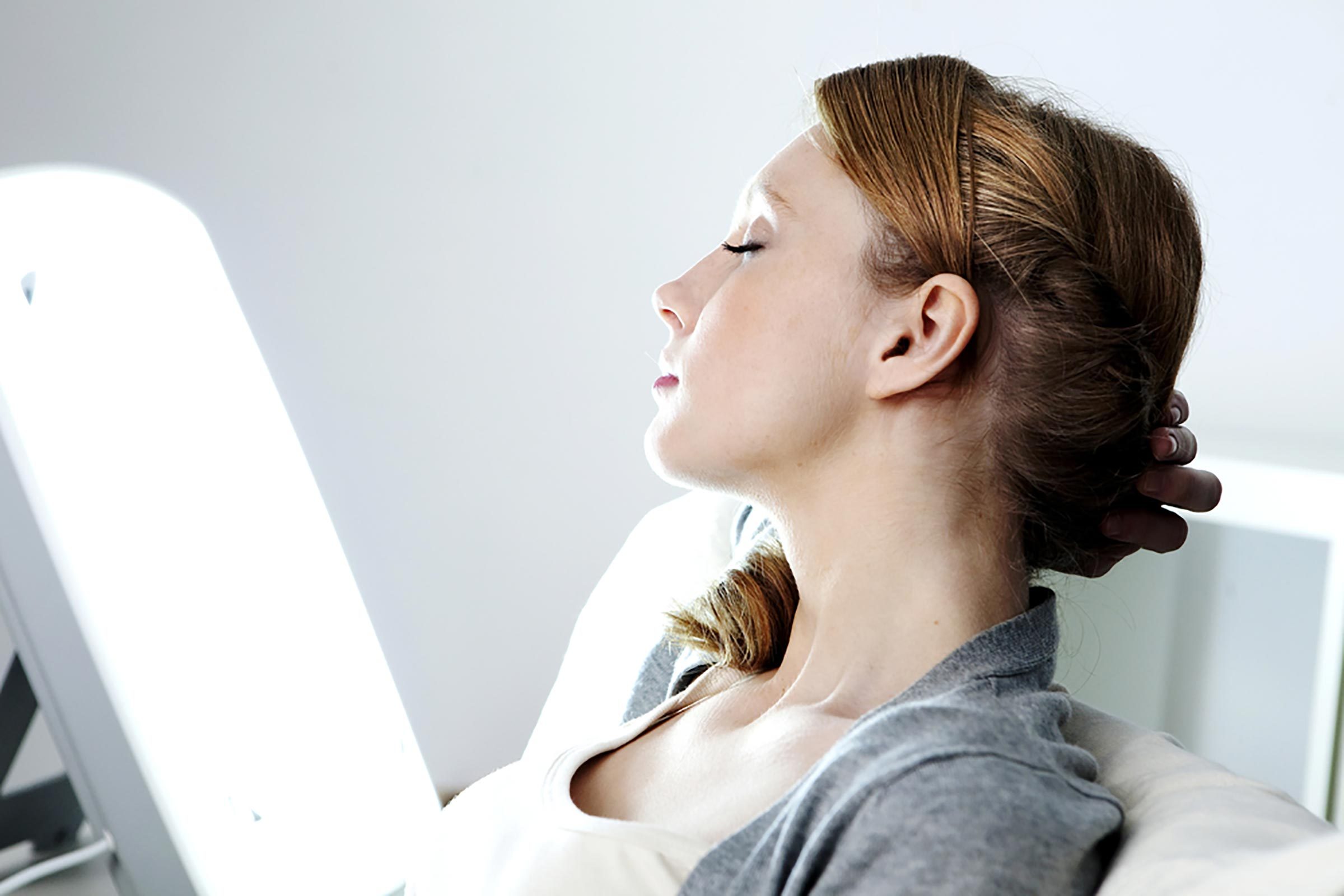 Woman with eyes closed receiving light therapy