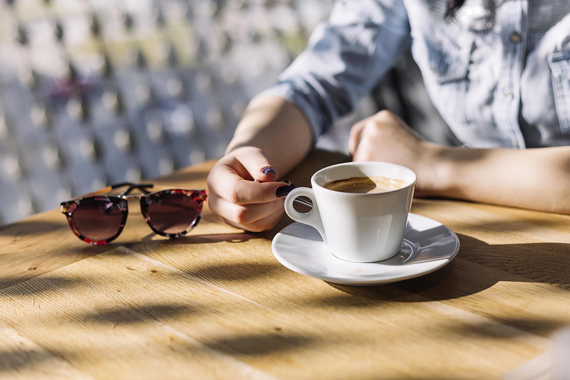 woman sitting at a table with a cup of coffee; outdoors