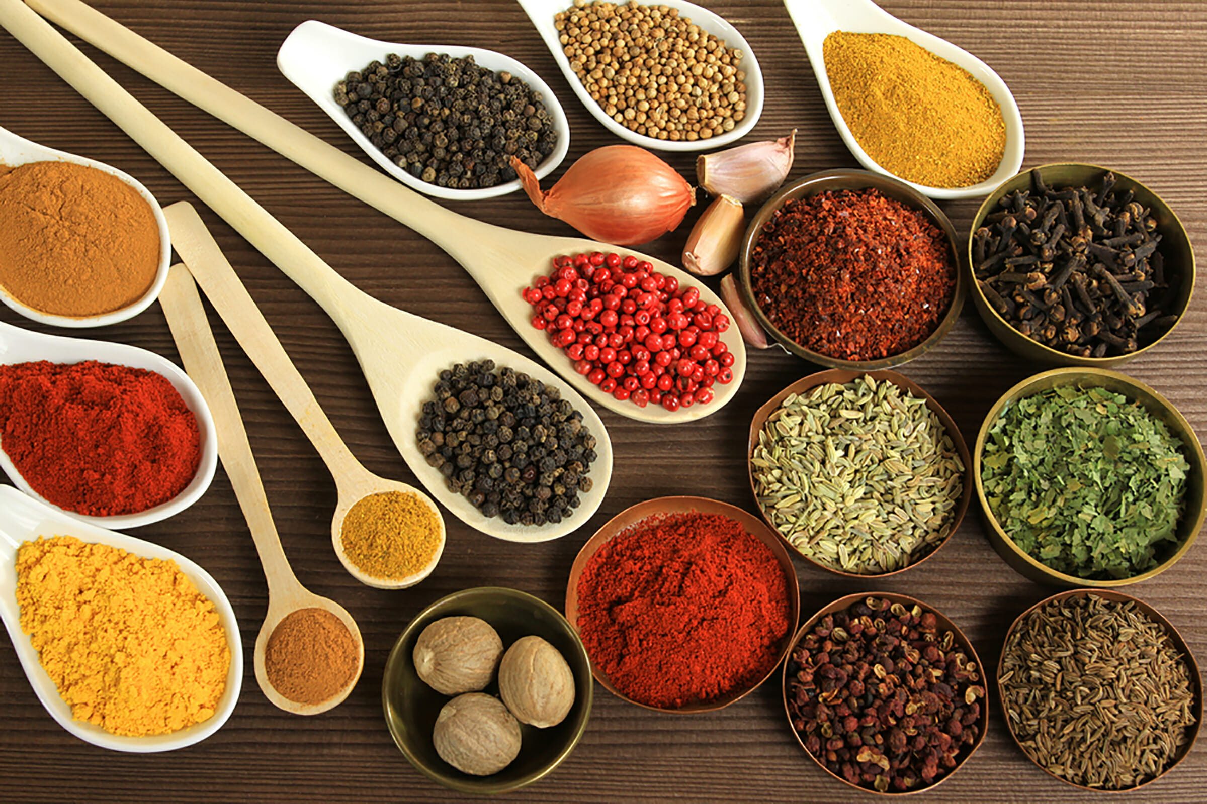 Bowls and spoons filled with different colored spices