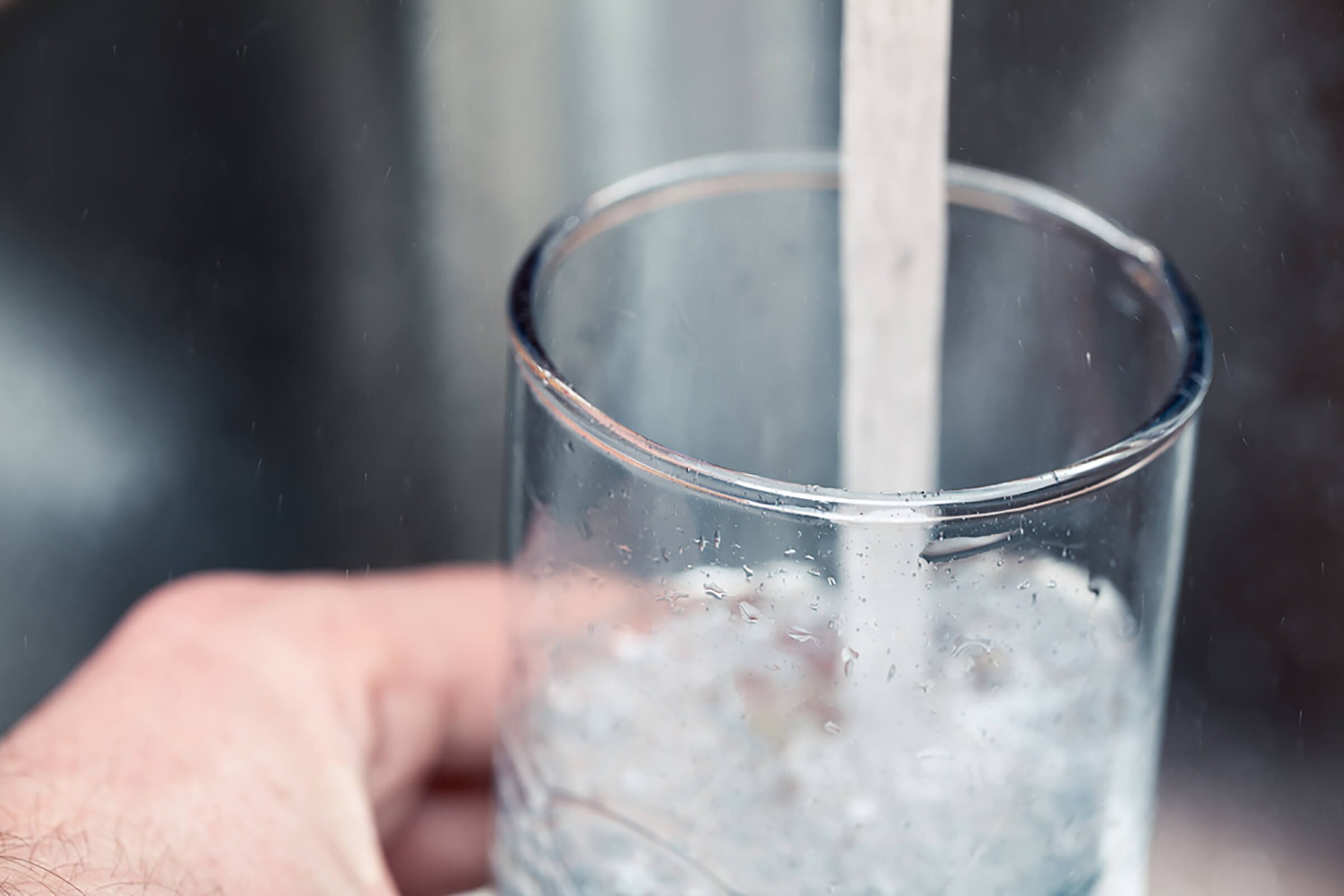 pouring glass of water from faucet