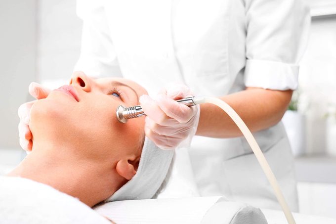 skin esthetician apply facial device on woman