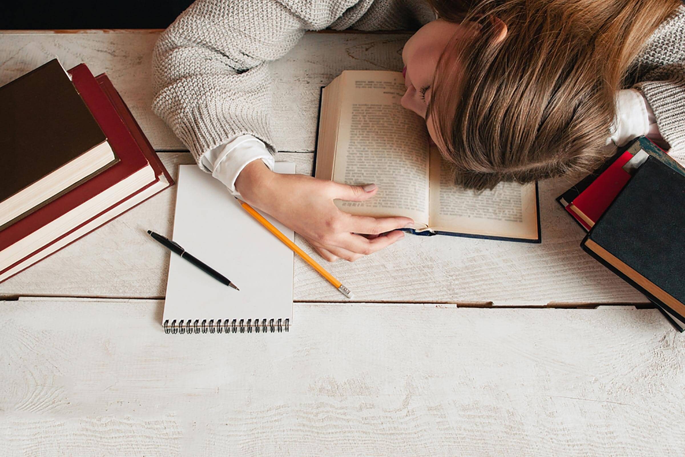 young woman asleep with head on books