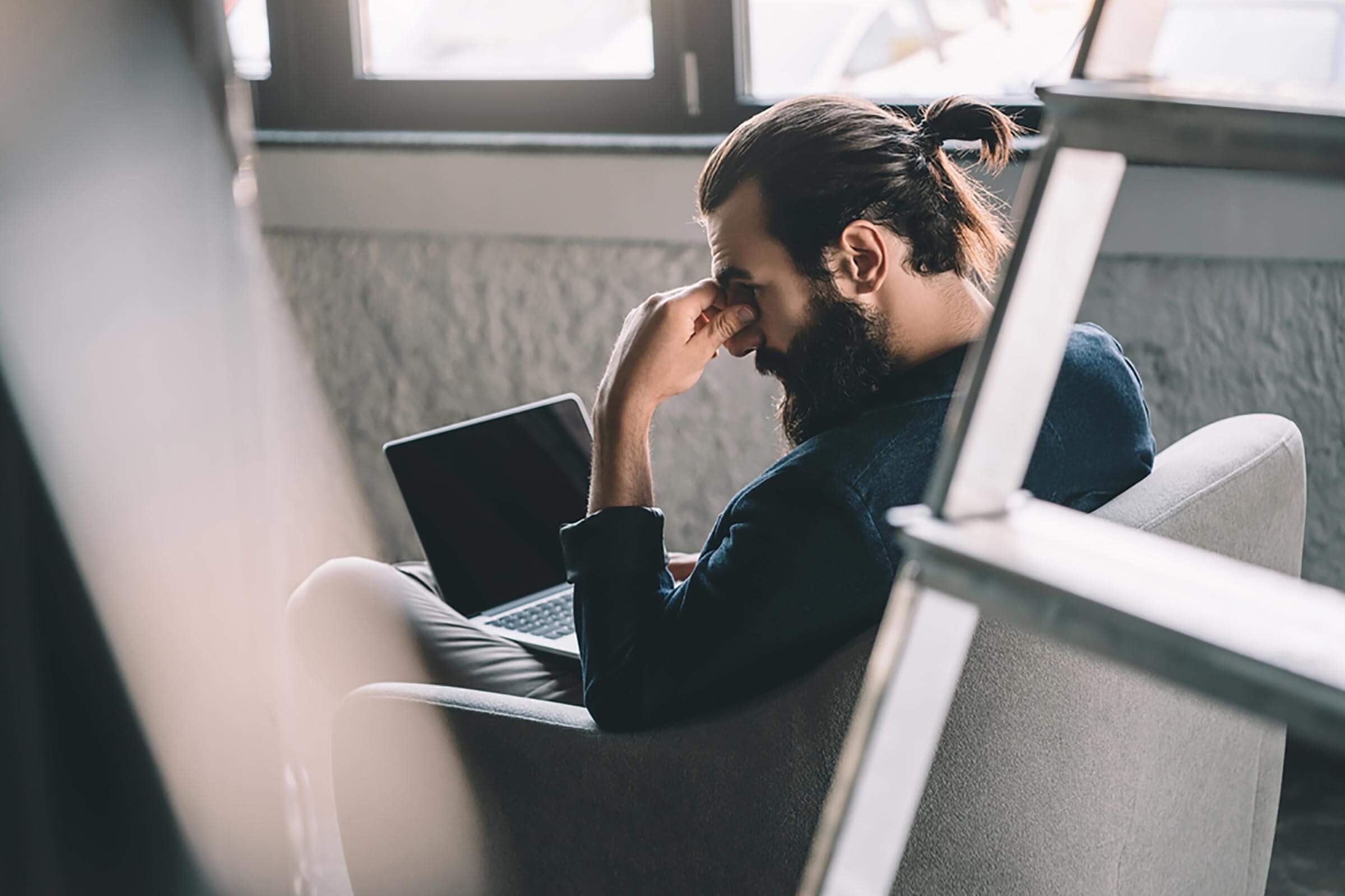 man with laptop holding head