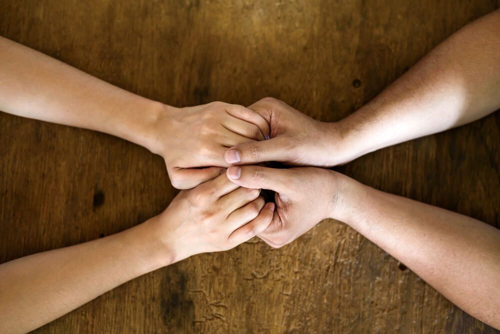 Close up on a couple hand holding hands on wooden table