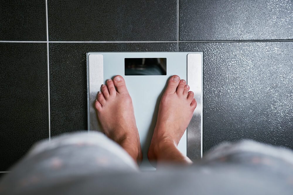 Female bare feet with weight scale, top view