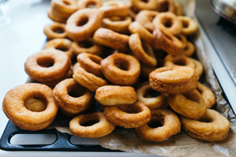 Fried donuts on a baking sheet. Donuts lie in several layers.