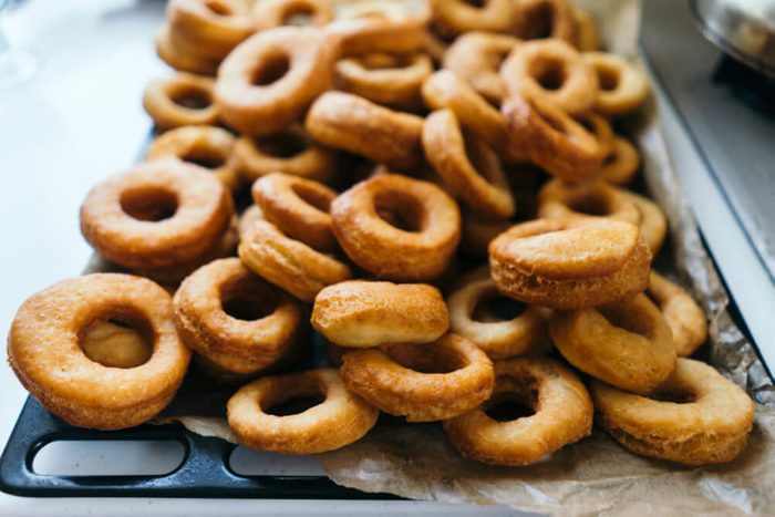 Fried donuts on a baking sheet. Donuts lie in several layers.