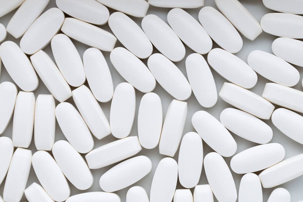 White pills on the white background.