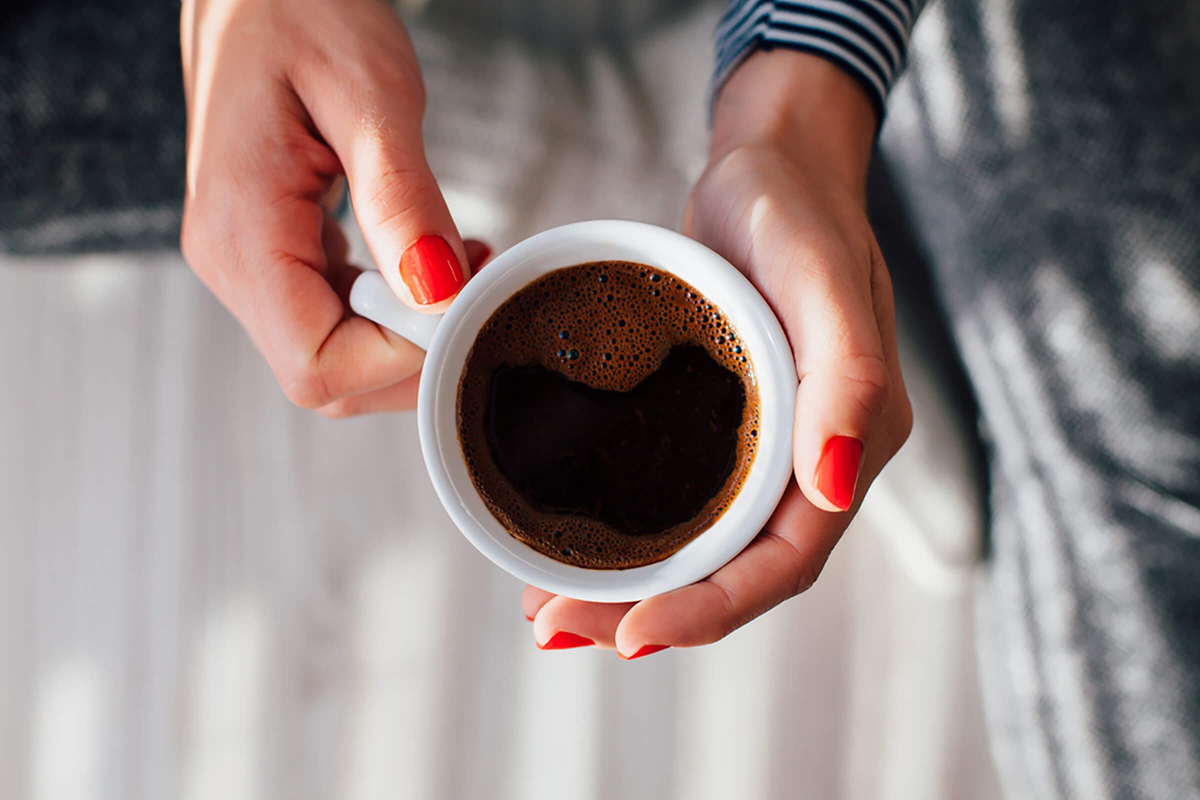 woman's hands holding cup of coffee