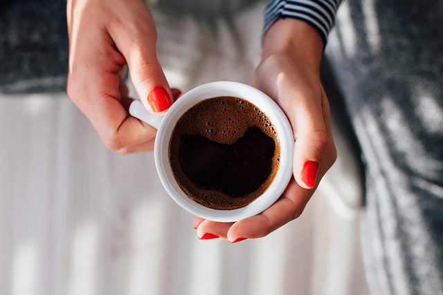 woman's hands holding cup of coffee