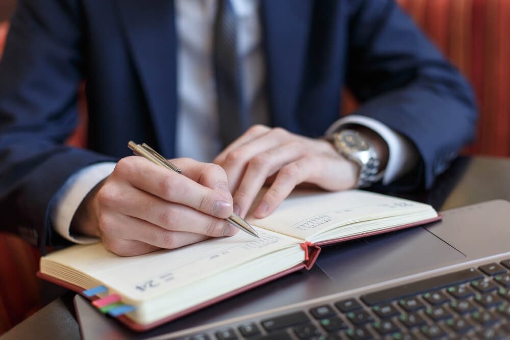 man writing in his planner book