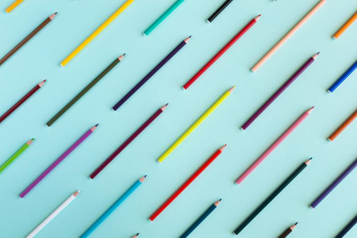 Colorful background with many crayons pastels lined up on azure aquamarine - Top view flat lay