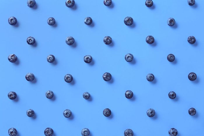 Colorful pattern of blueberries on blue background. From top view