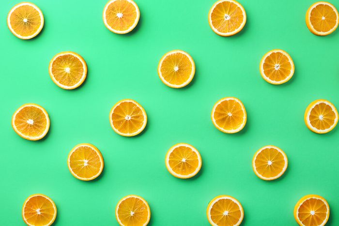 Colorful fruit pattern of fresh orange slices on green background. From top view