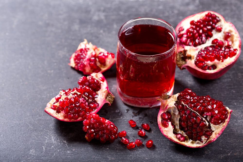 glass of pomegranate juice with fresh fruits on dark background.