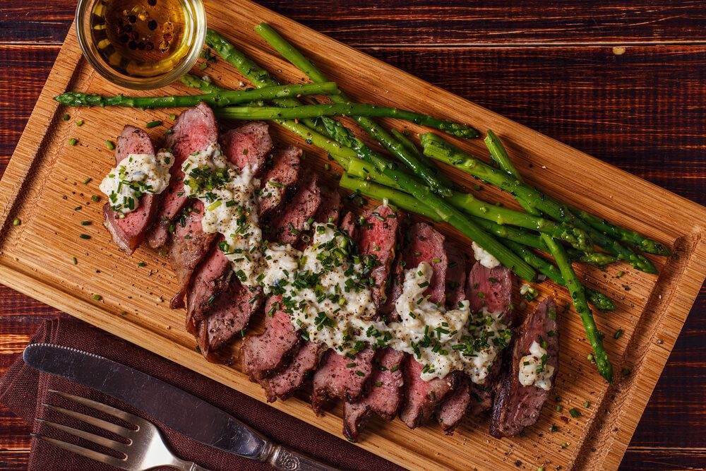 Steak with blue cheese sauce served with asparagus on dark background.