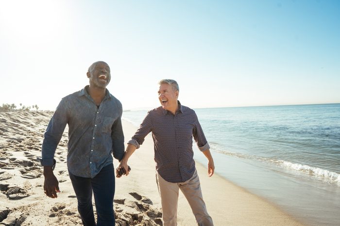 senior same sex couple holding hands on the beach