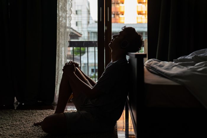 silhouette of a man sitting at the foot of the bed