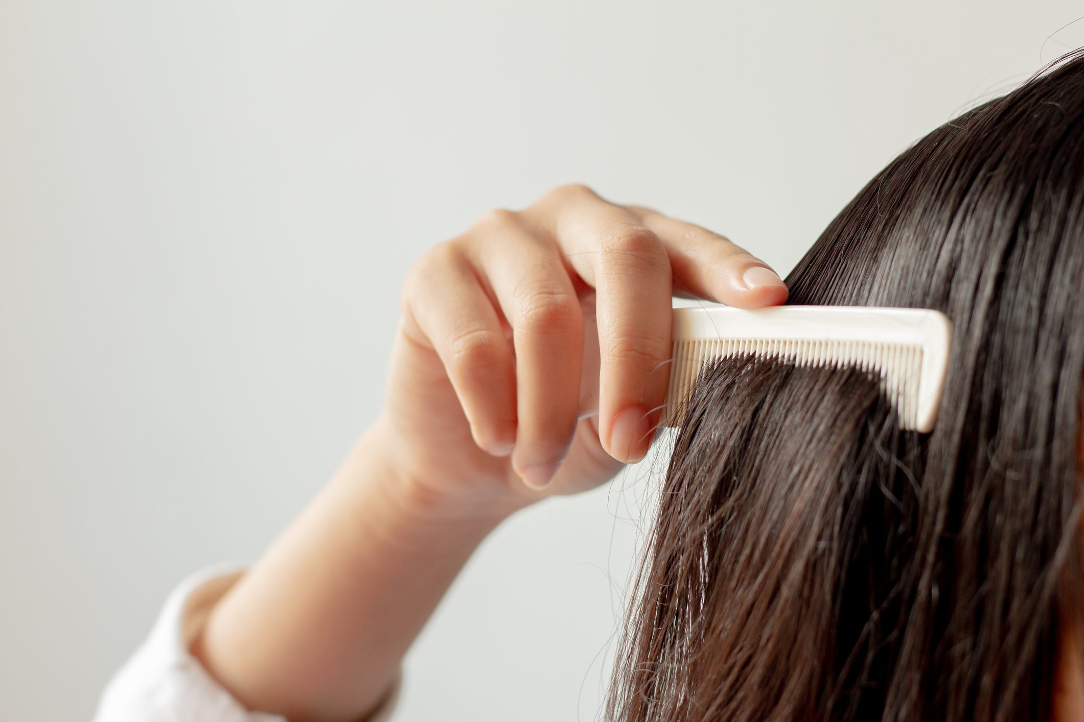 woman's hand running comb through hair