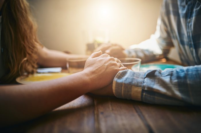 couple holding hands at dinner table