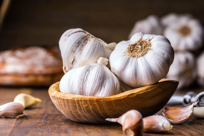 Garlic Cloves and Garlic Bulb in vintage wooden bowl.