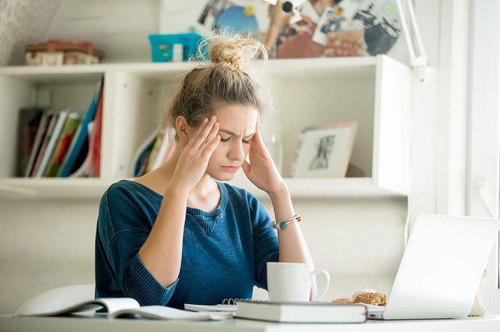 woman holding her temples and wincing in pain