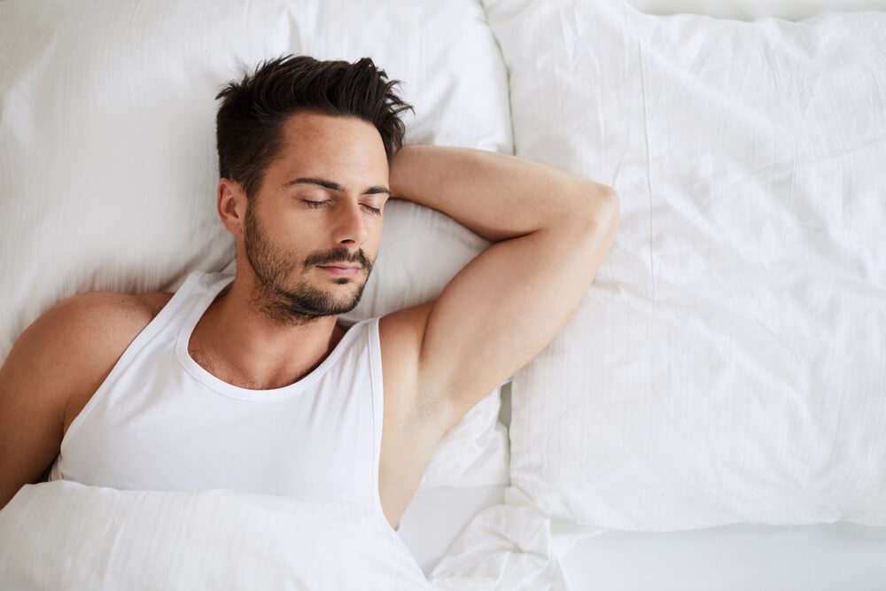 Top view of handsome young man sleeping with his hand tucked under head