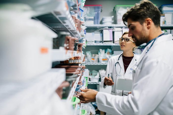 Two pharmacist working in drugstore. Male and female pharmacists checking medicines inventory at hospital pharmacy.