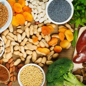 Collection iron rich foods as liver, buckwheat, eggs, parsley leaves,dried apricots, cocoa, lentil, bean, blue poppy seed, broccoli, dried mushrooms, peanuts and pistachios on wooden table.