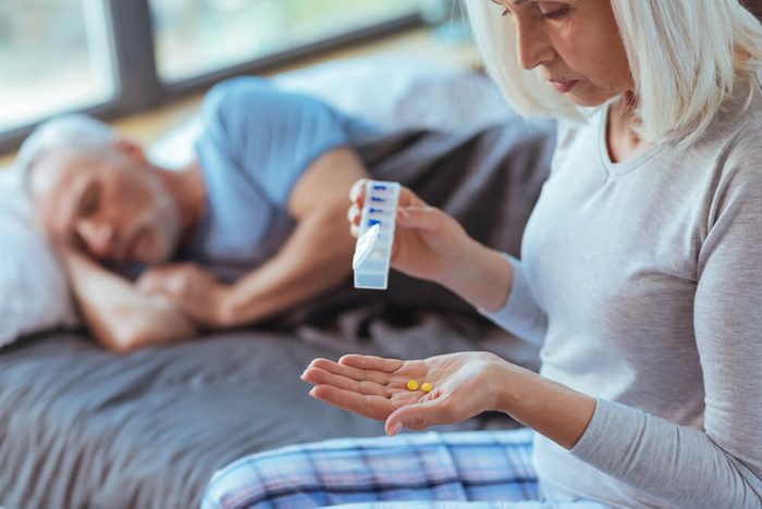 Cheerless aged woman holding pills for her husband