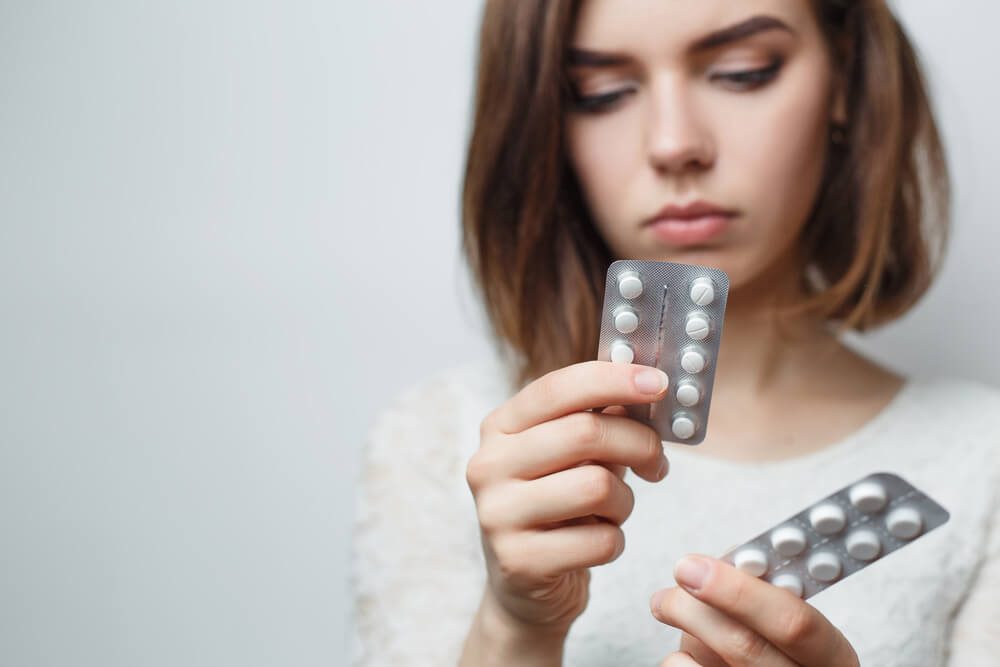 Young girl reading the name holding a pill in her hands