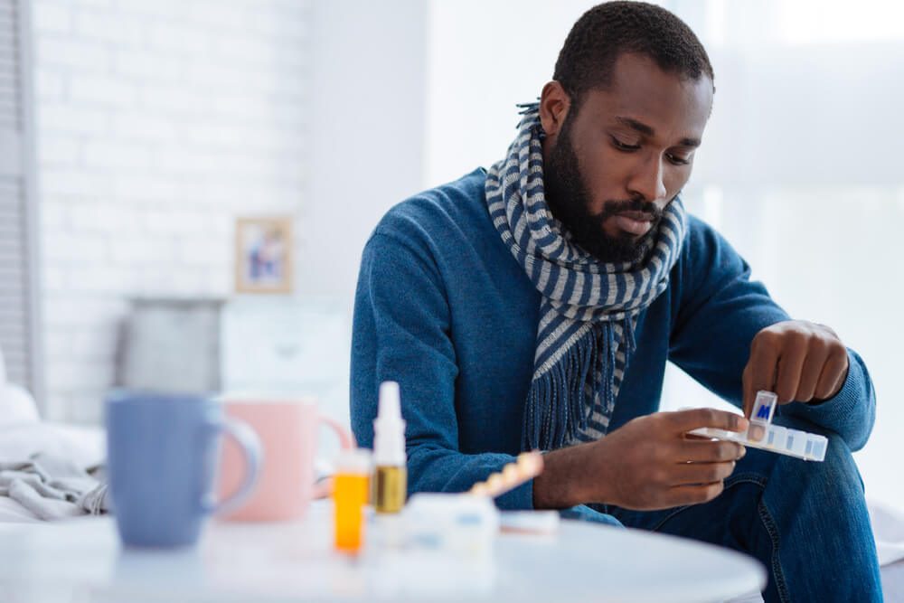 Serious calm man taking a pill from a pill box