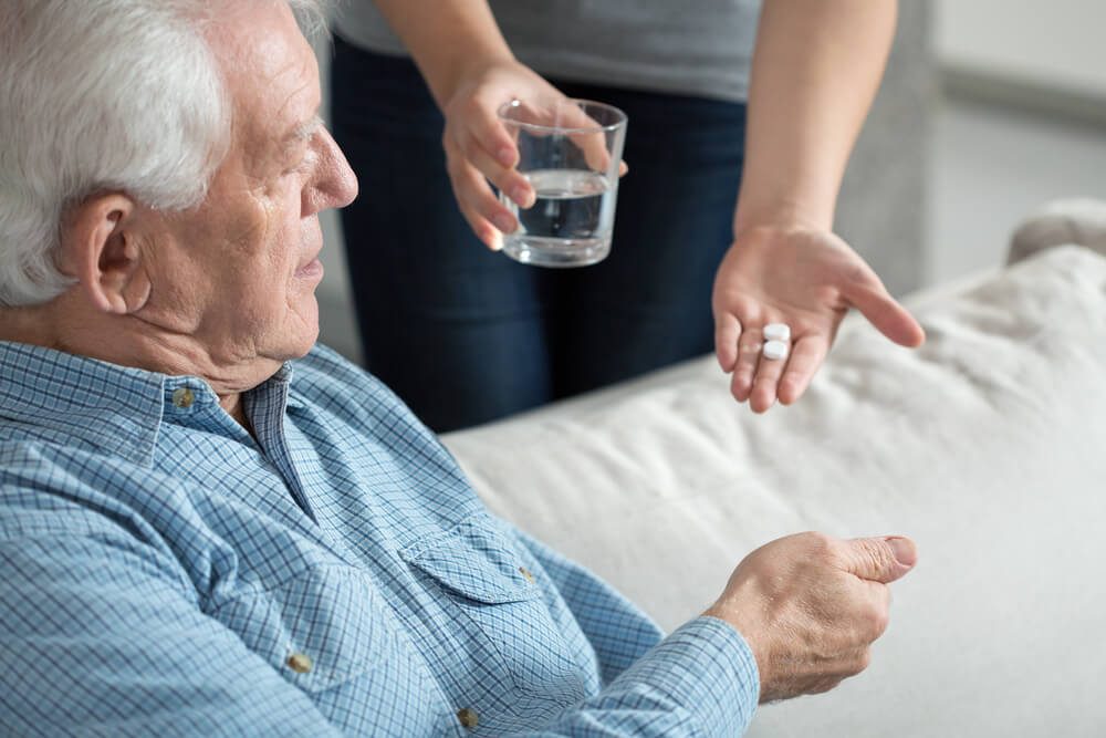 Female caregiver giving the medicine to her older male patient