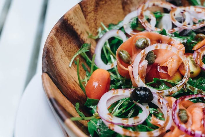 Smoked salmon salad with red onion, capers, lemon and arugula.and green rocket