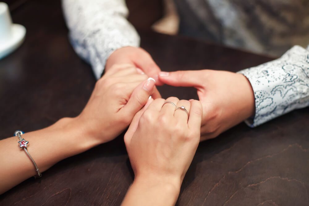 Young couple in love clasping hands across the table in cafe.